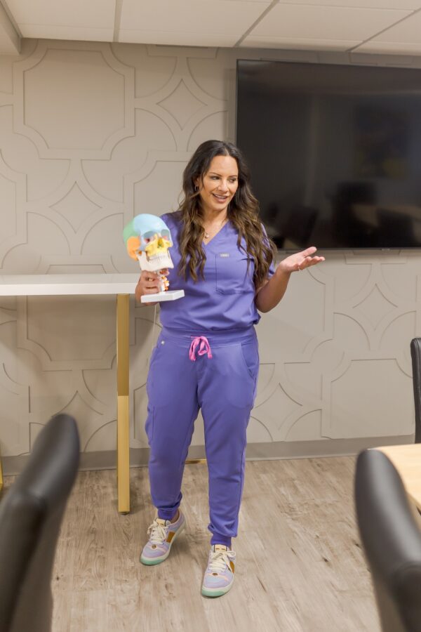 Aesthetics Trainer holding a skull to teach anatomy at training academy for nurses, doctors, pa's.