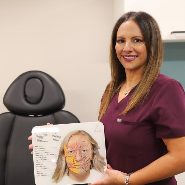 Dr. Stef Gatica, DNP, holding up facial anatomy diagram