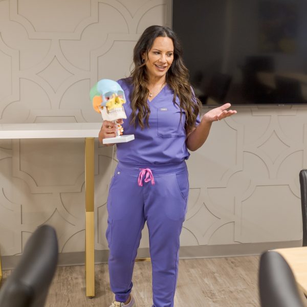 Aesthetics Trainer holding a skull to teach anatomy at training academy for nurses, doctors, pa's.